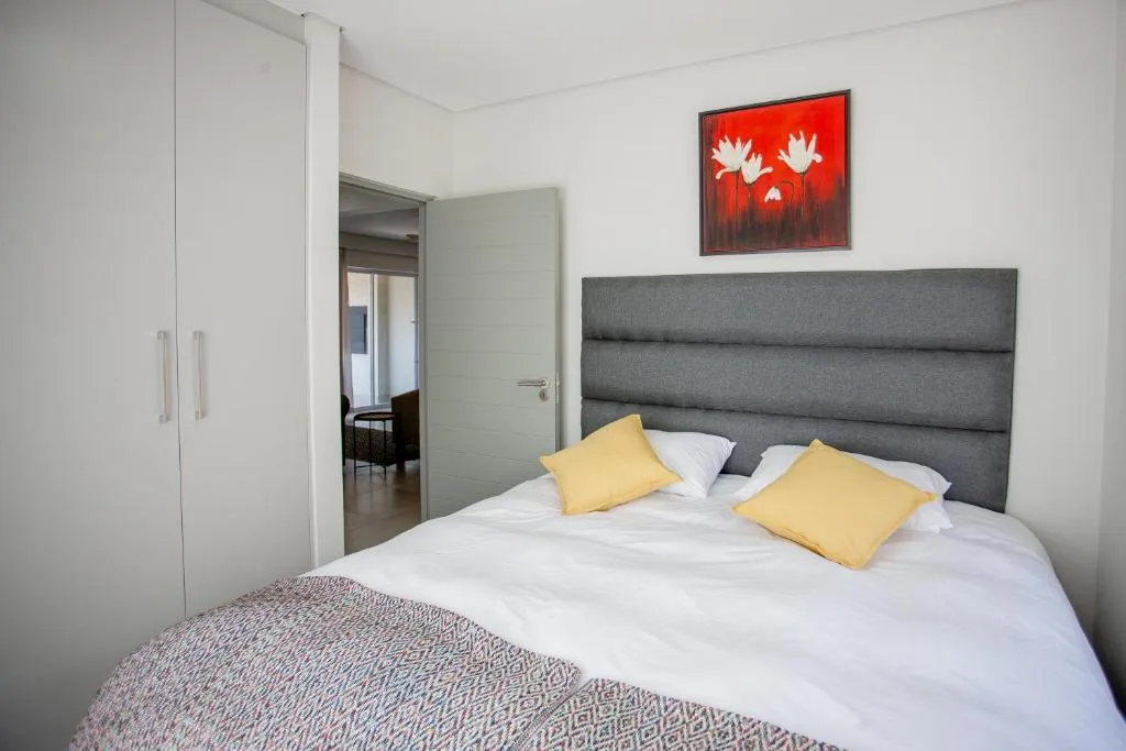 Bright bedroom with gray upholstered headboard and yellow accent pillows