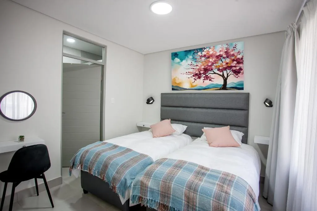 Modern bedroom with gray upholstered bed, white linens, and colorful tree artwork