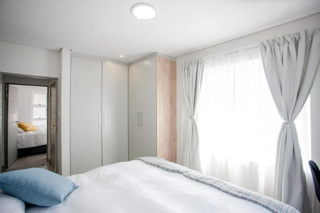 Bright modern bedroom with white bedding and blue pillow accent
