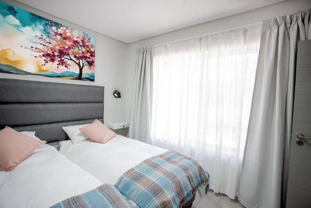 Modern bedroom with gray upholstered headboard and colorful tree artwork above