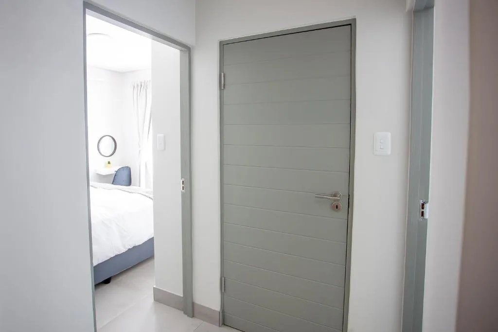 Modern hallway with gray doors and white walls leading to bedroom