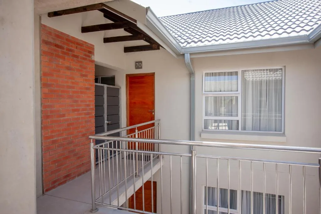 Modern apartment entrance with red brick wall and metal staircase railing