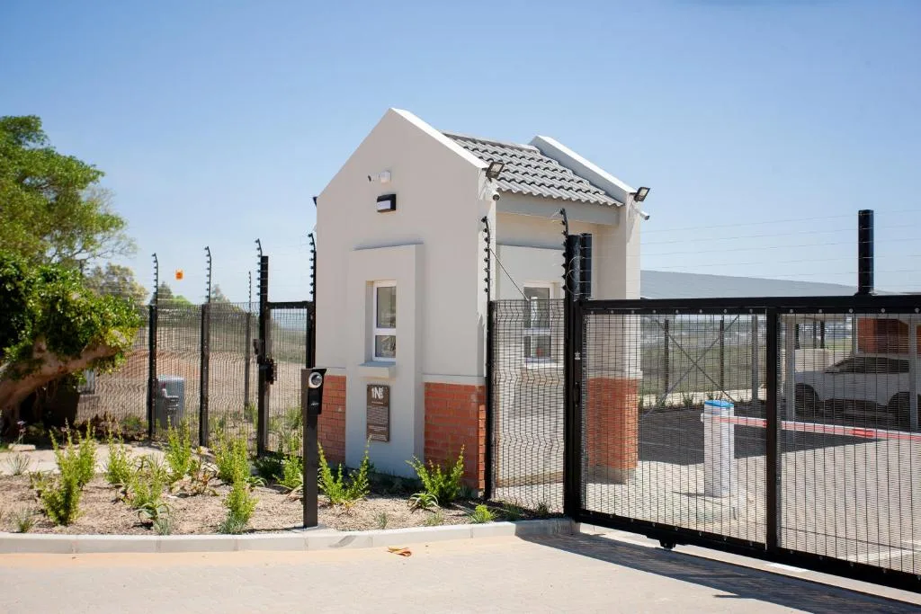 Modern white cottage with red brick base and black security fencing
