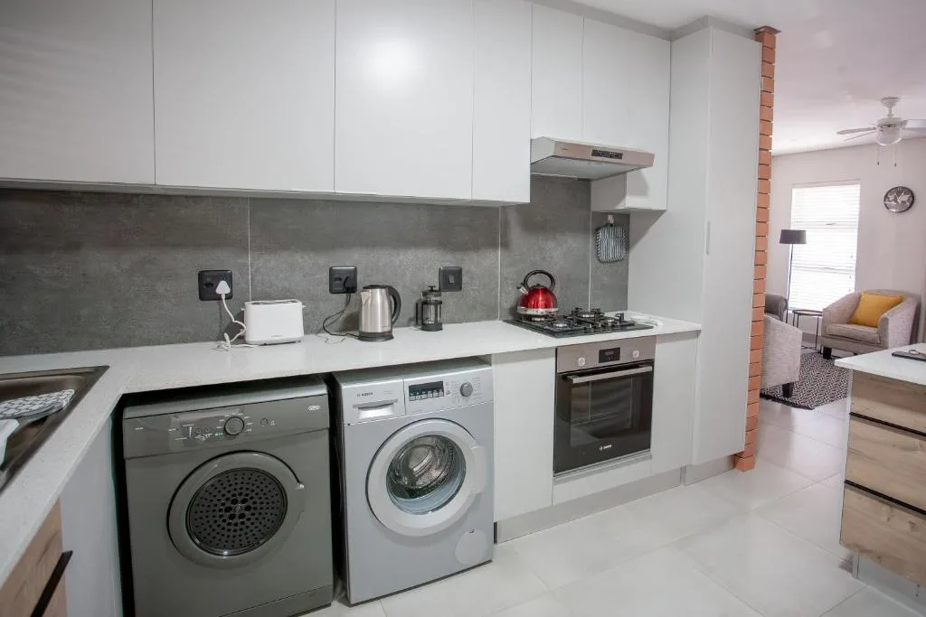 Modern kitchen with white cabinetry, gas stove, and integrated laundry appliances