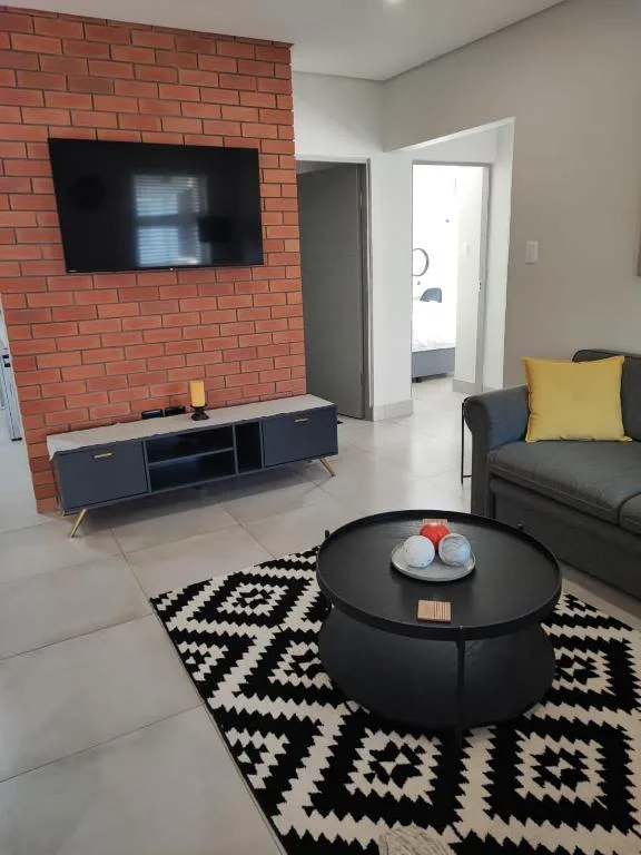 Modern lounge with brick fireplace, wall-mounted TV, and contemporary seating