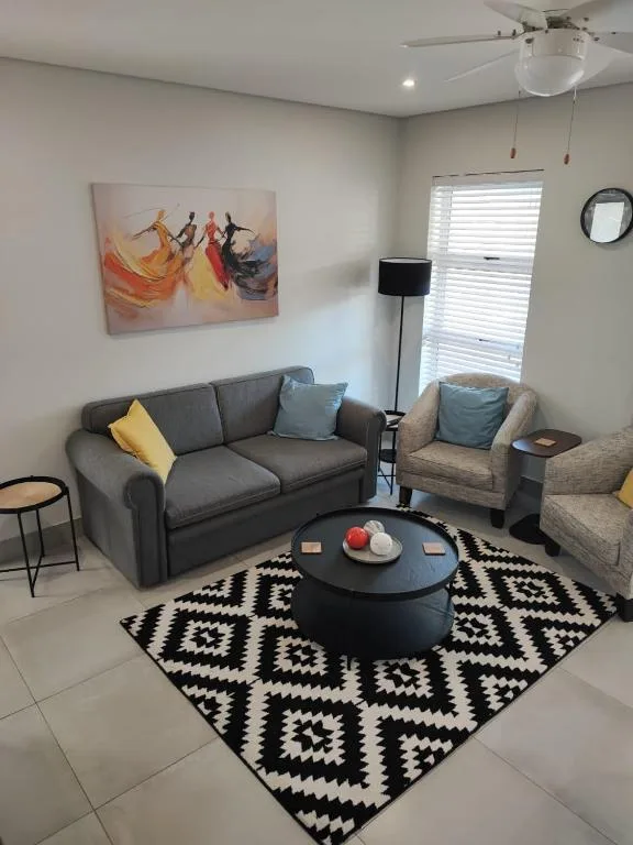 Modern lounge with gray sofa, armchair, geometric rug, and artwork