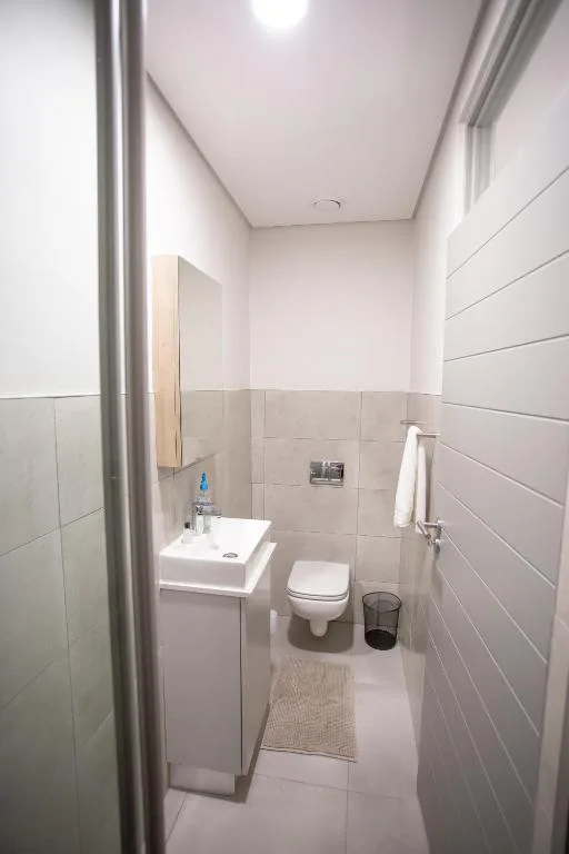 Modern white bathroom with vanity sink, toilet, and tiled walls