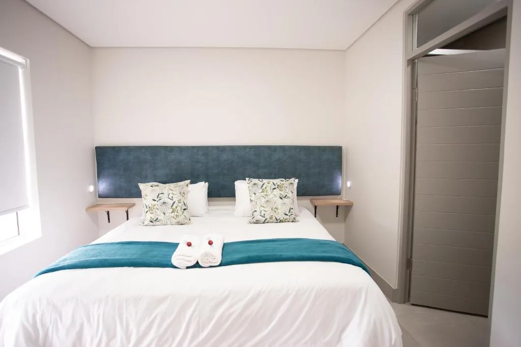 Modern bedroom with blue upholstered headboard and white bedding arrangement