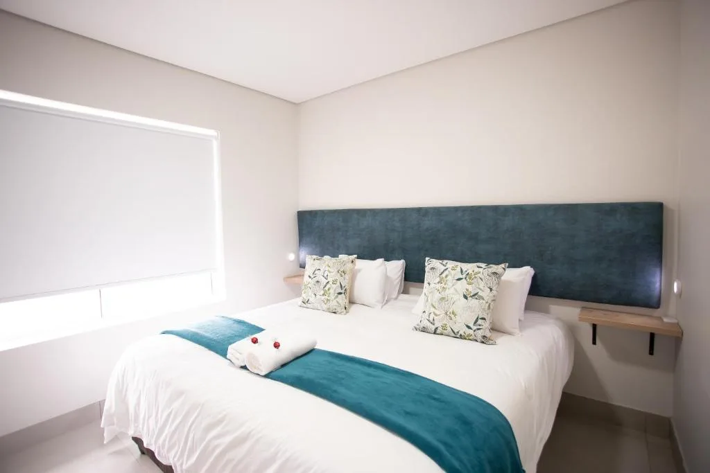 Modern bedroom with queen bed, dark headboard, white linens, and decorative pillows