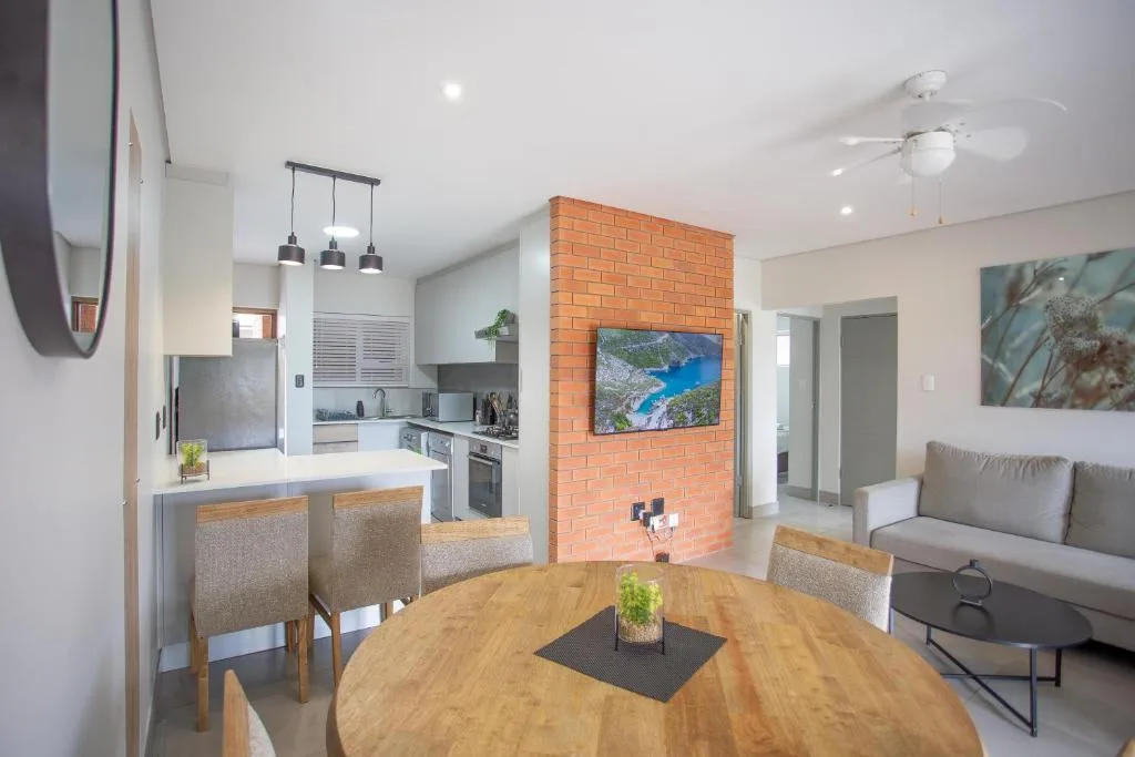 Open-plan dining area with round wooden table and upholstered chairs