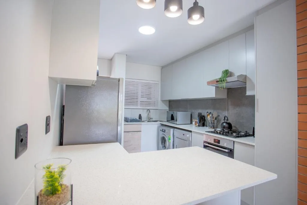 Modern kitchen with white cabinetry, stainless steel appliances, and grey backsplash