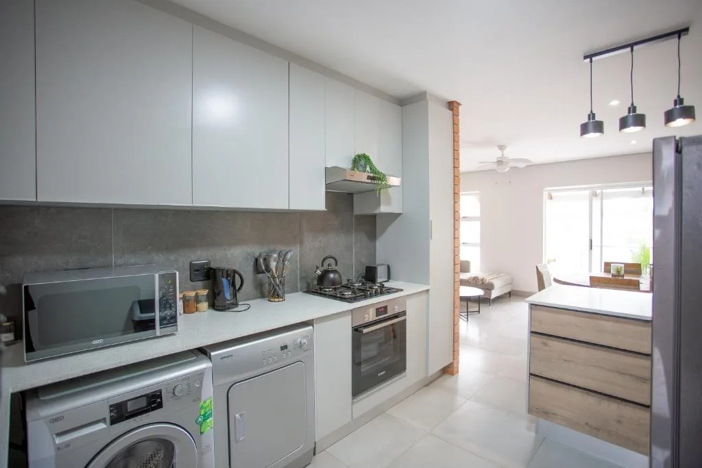 Modern kitchen with white cabinets, stainless steel appliances, and open-plan living area view