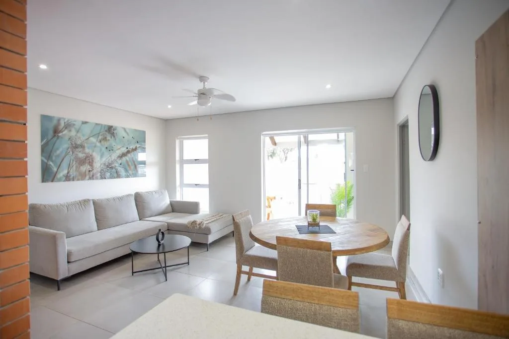 Modern lounge with gray sofa, dining table, and glass doors to outdoor space