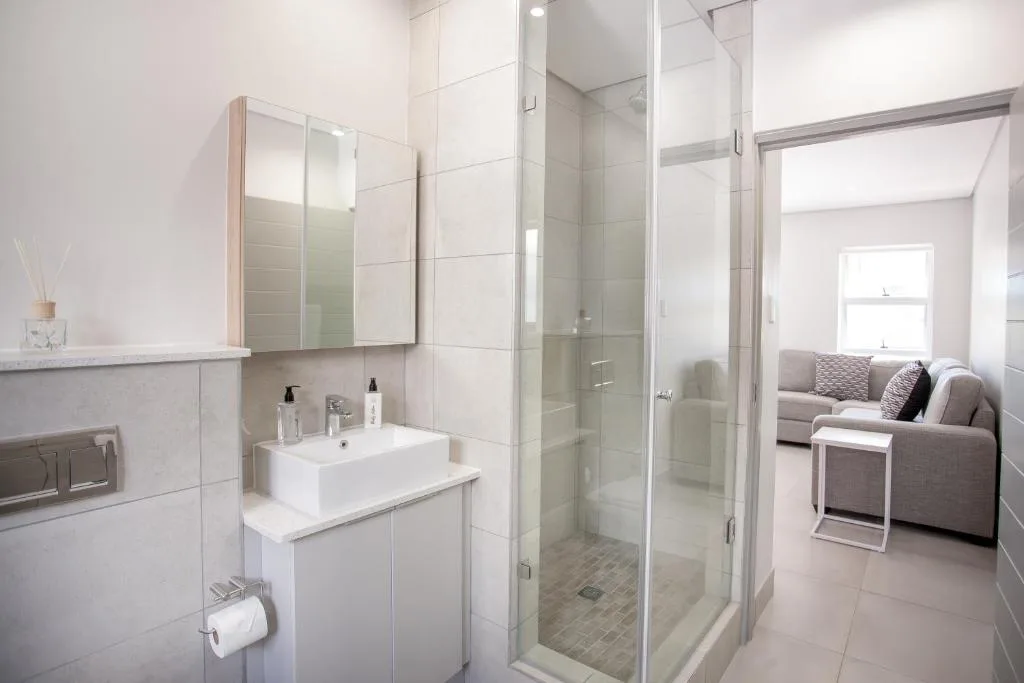 Modern bathroom with white vanity, mirror cabinet, and walk-in shower