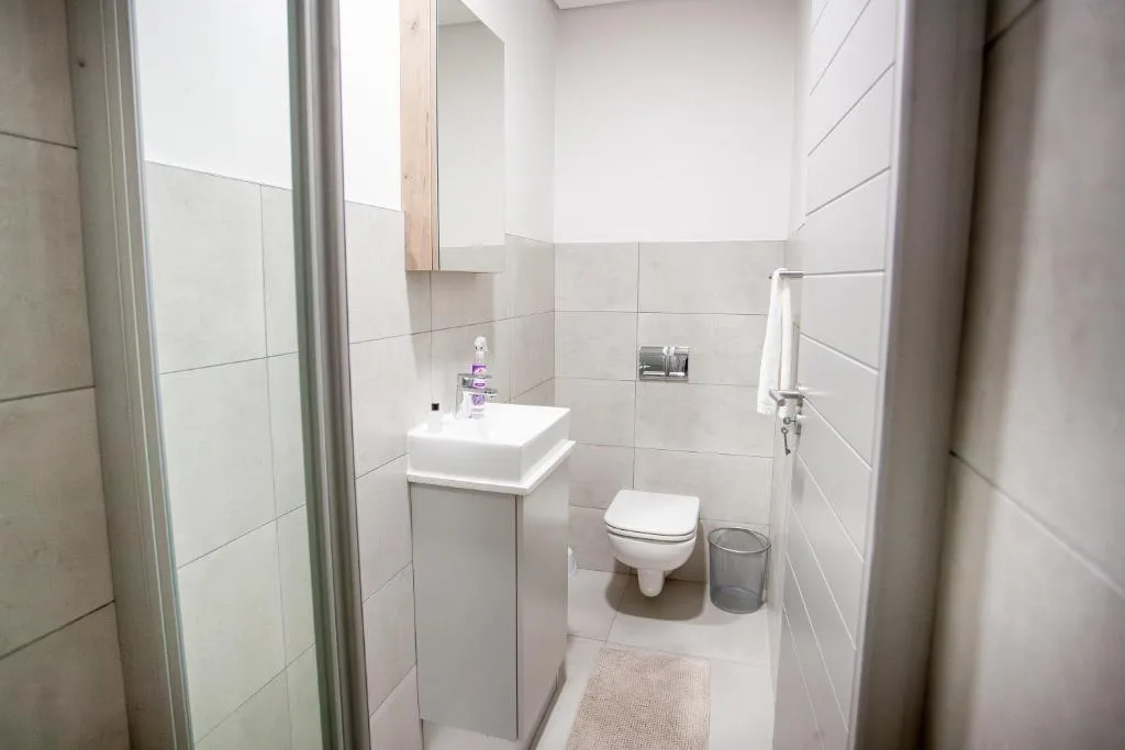 Modern bathroom with white tile walls, vanity sink, and toilet