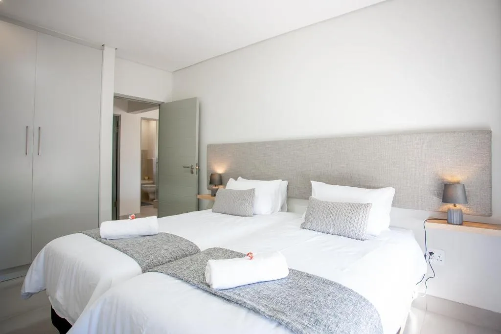 Modern bedroom with two twin beds, neutral decor, and ensuite bathroom access