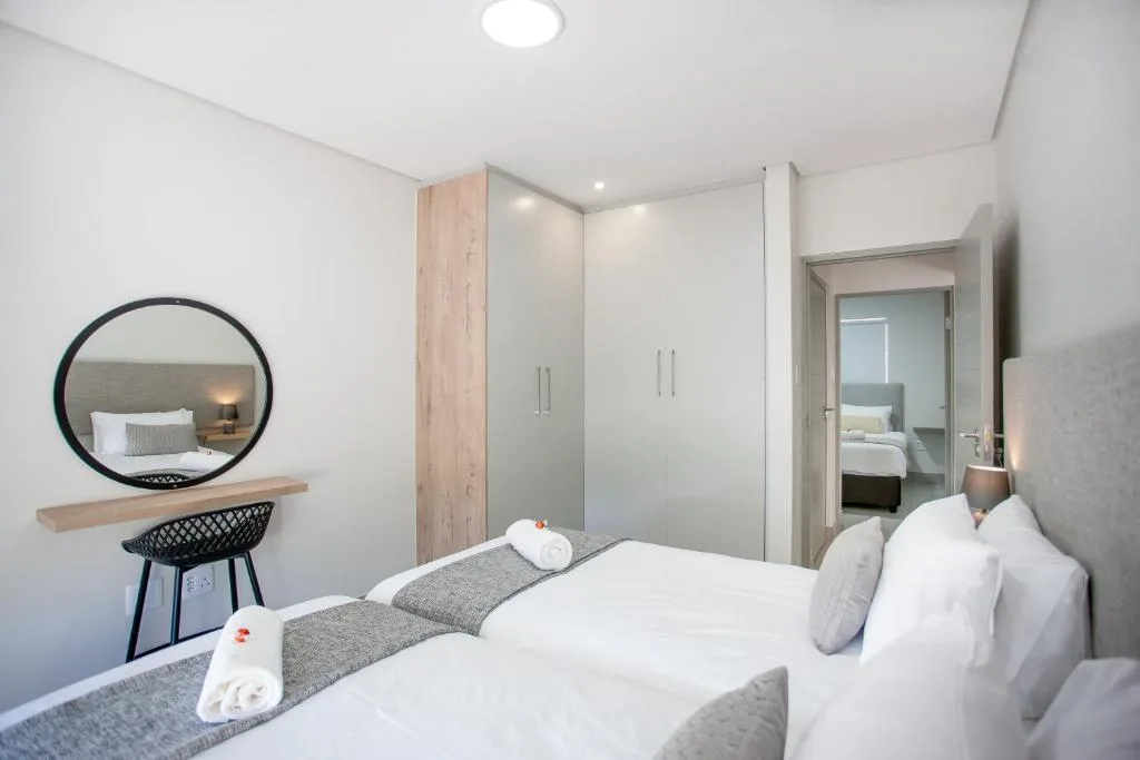 Modern bedroom with double bed, round mirror, and ensuite bathroom visible