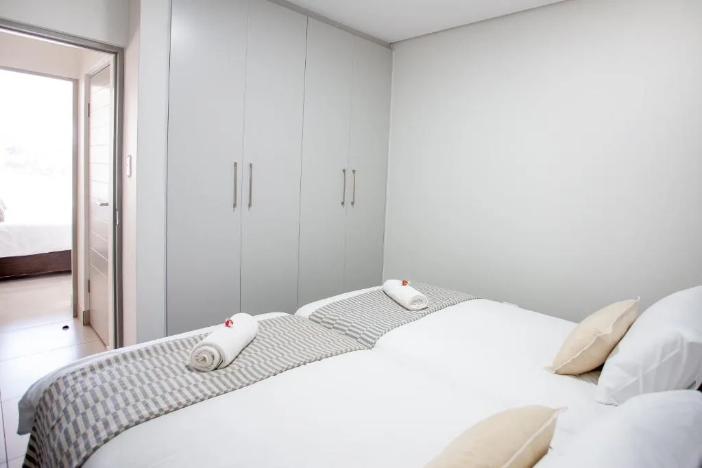 Modern bedroom with twin beds, white linens, and built-in wardrobe