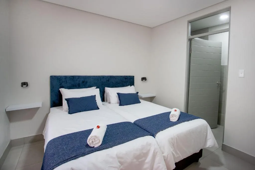 Modern bedroom with blue upholstered headboard and white bedding