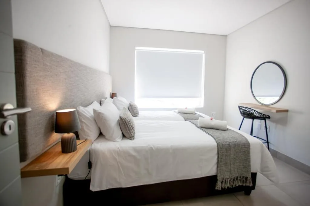 Modern bedroom with white linens, upholstered headboard, and natural light