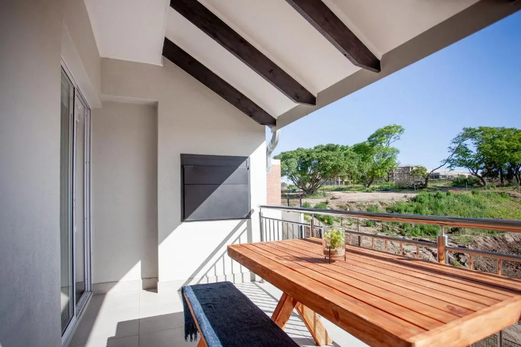Modern wooden deck with dining table overlooking rural landscape and trees