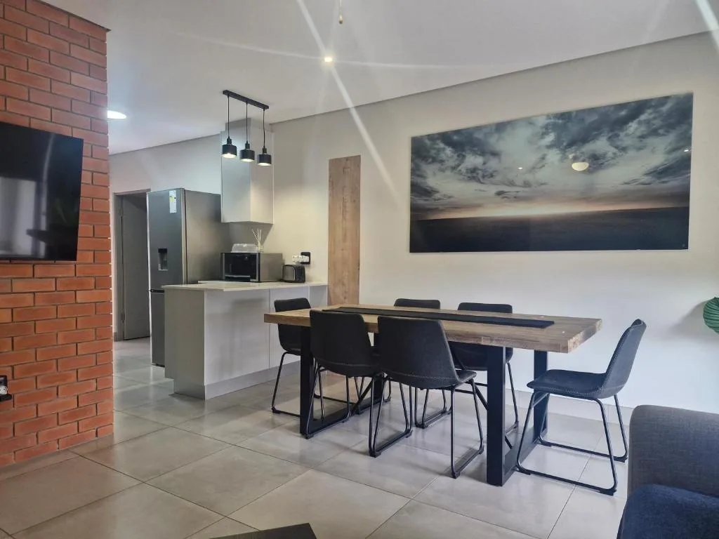 Modern dining table with black chairs and scenic artwork on wall