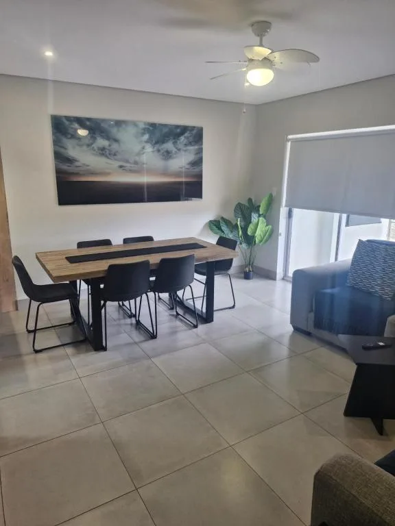 Modern dining area with wooden table and black chairs, artwork on wall