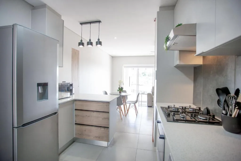 Modern open-plan kitchen with white cabinetry, stainless steel appliances, and pendant lighting