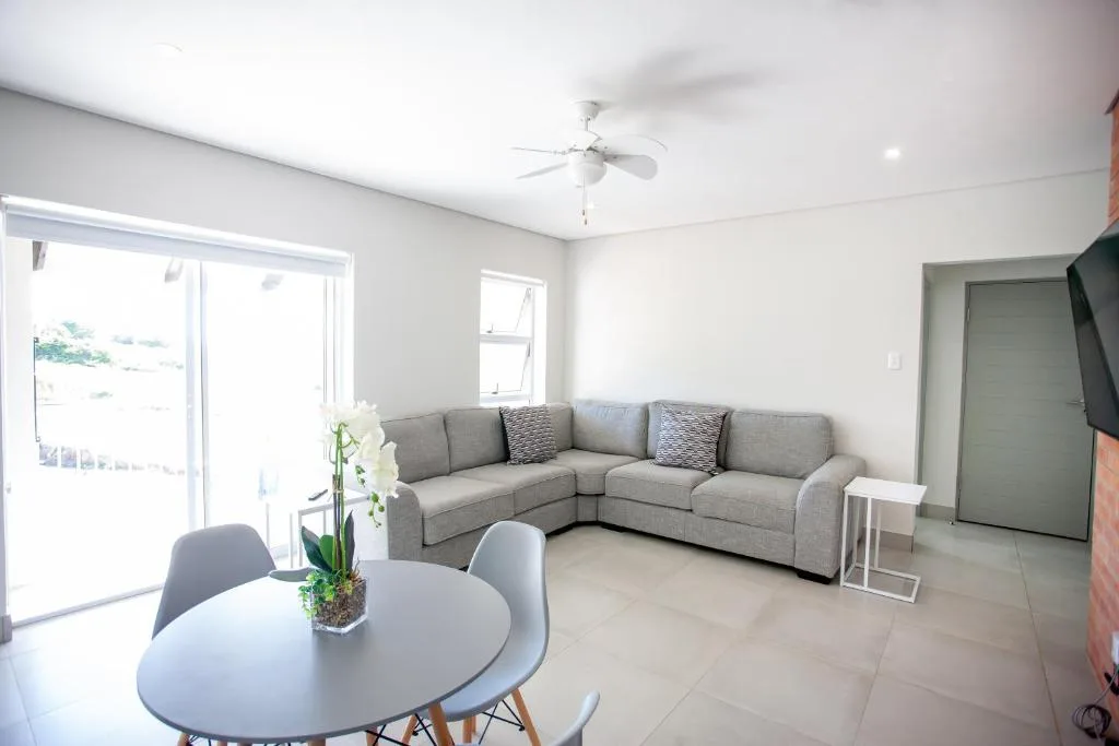 Bright open-plan lounge with gray sectional sofa and dining table