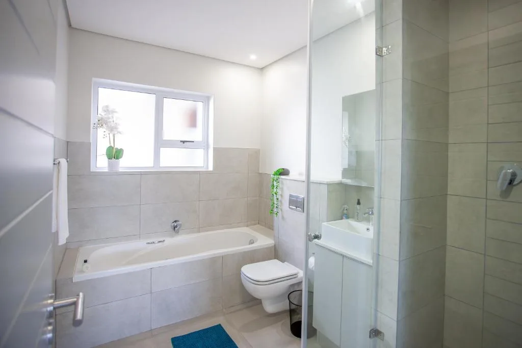 Modern bathroom with bathtub, toilet, sink, and glass shower enclosure