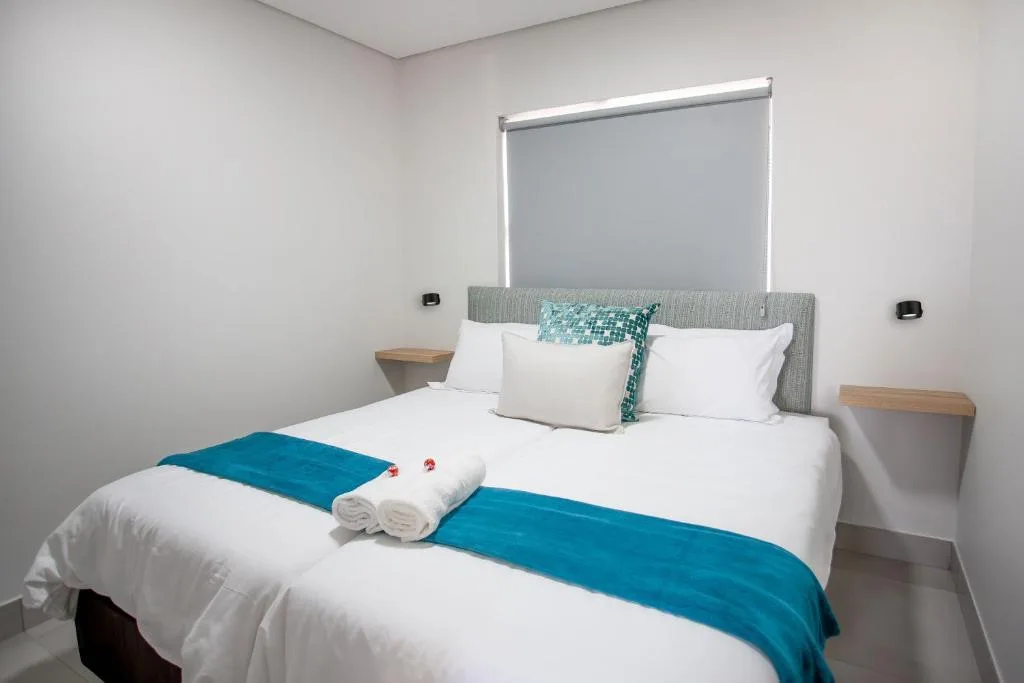 Modern bedroom with queen bed, white linens, blue accents, and bedside tables