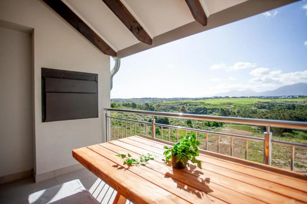 Wooden deck with potted plant overlooking sprawling green valley landscape
