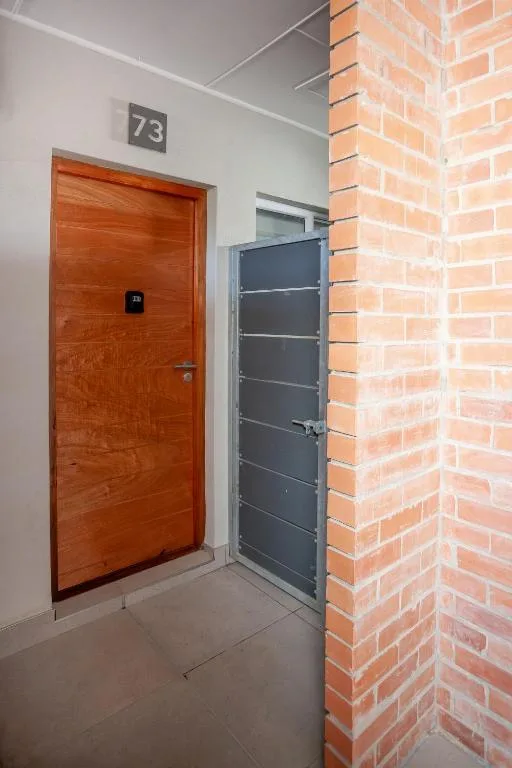 Modern apartment entrance with red wooden door and brick wall