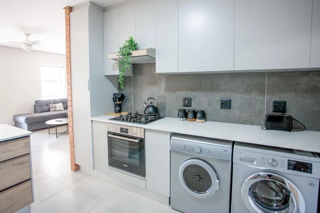 Modern kitchen with gas stove, washing machines, and white cabinetry