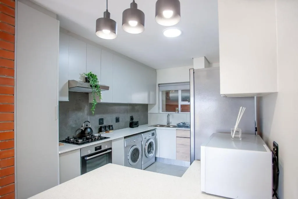 Modern white kitchen with gas stove, washer-dryer, pendant lighting