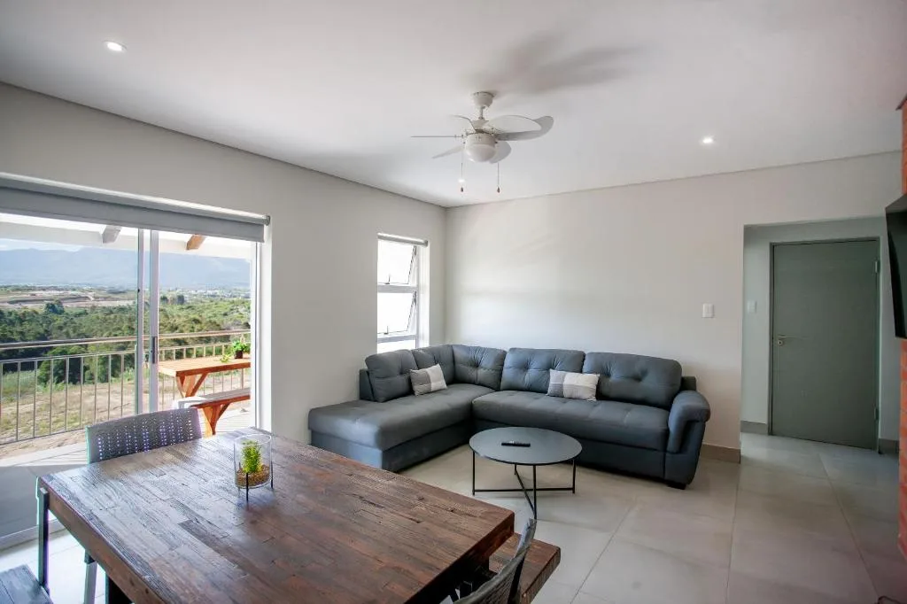 Modern lounge with dark sectional sofa, wooden table, and scenic landscape views