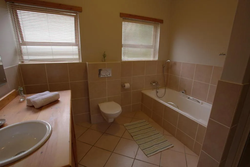 Spacious bathroom with bathtub, toilet, sink, and natural light from windows