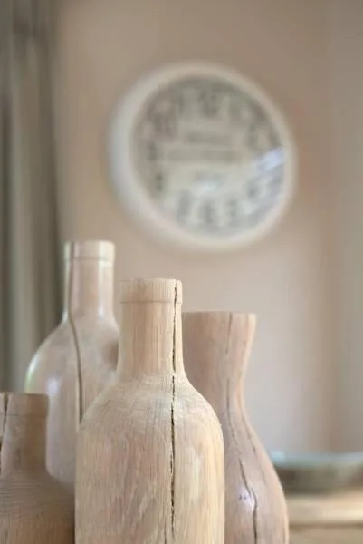 Wooden decorative bottles and clock on neutral wall shelf