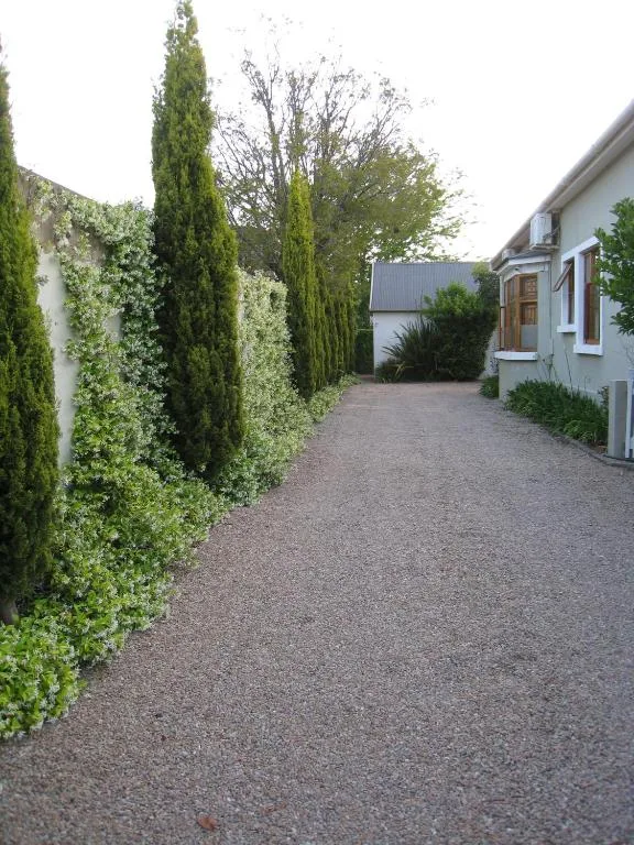 Driveway with manicured hedges leading to cottage entrance