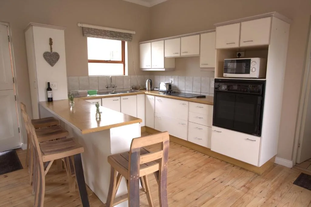 Modern kitchen with white cabinetry, wooden countertops, and black oven appliance