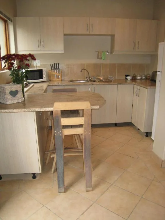 Modern kitchen with cream cabinetry, granite countertops, and wooden bar stool seating
