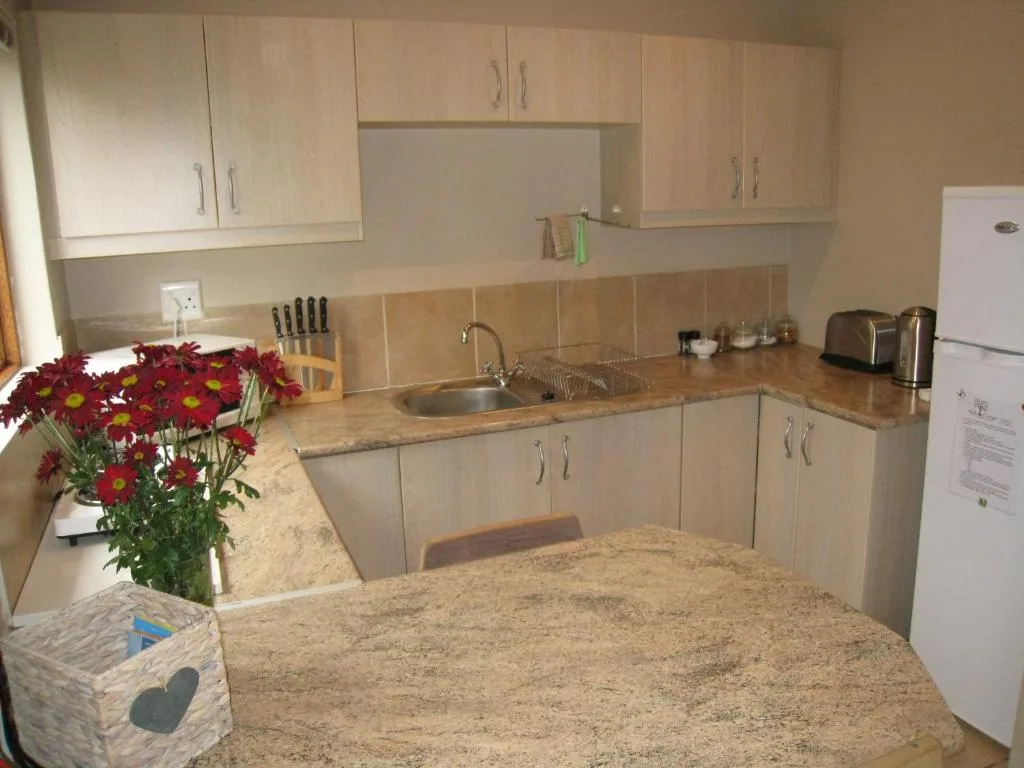 Spacious kitchen with light cabinetry, granite countertops, and fresh red flowers