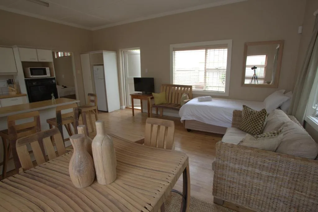 Open-plan lounge with sofa, dining table, and bed visible in background