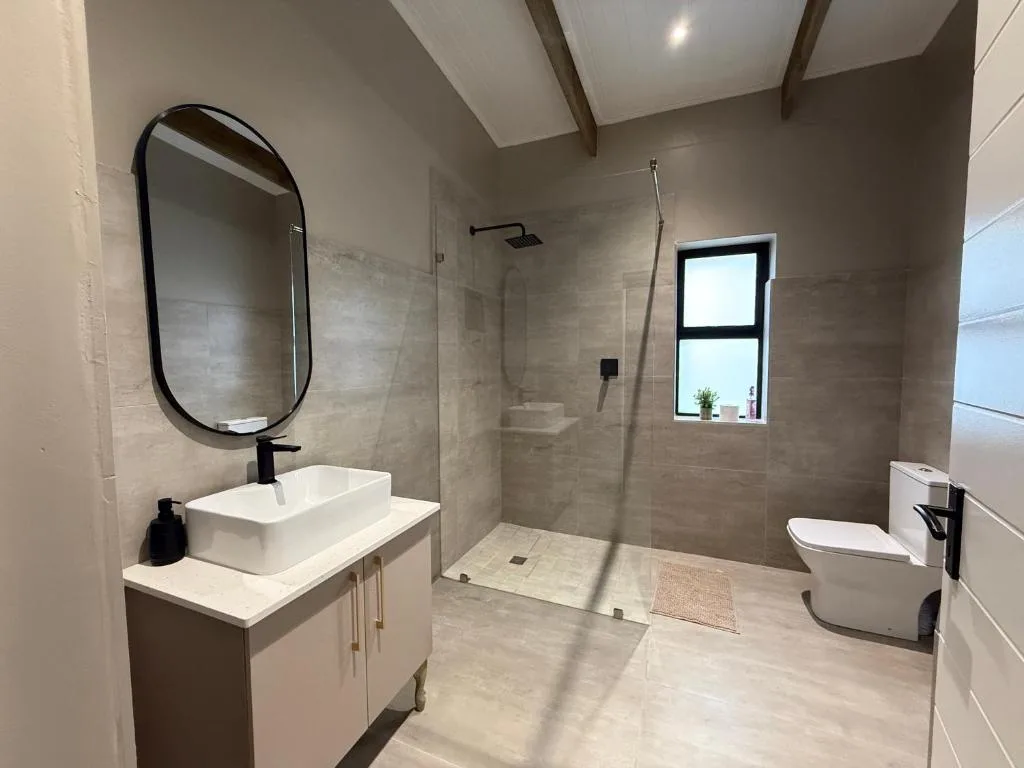 Modern bathroom with walk-in shower, white vanity, and round mirror