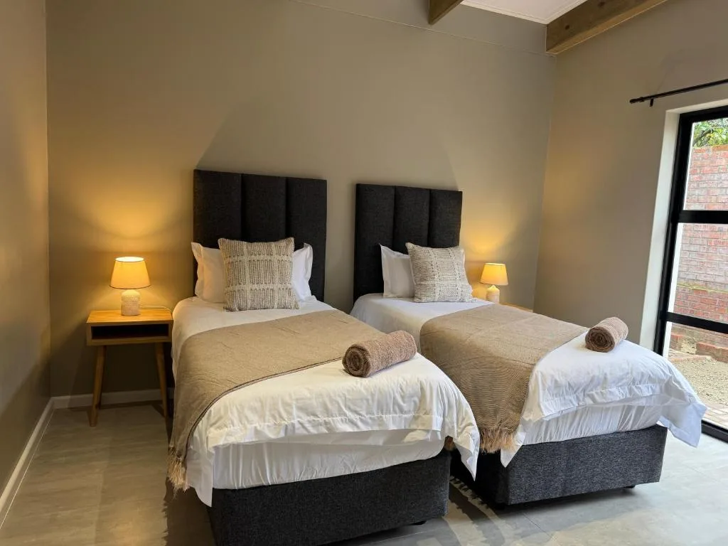 Twin bedroom with black headboards, warm lighting, and modern furnishings