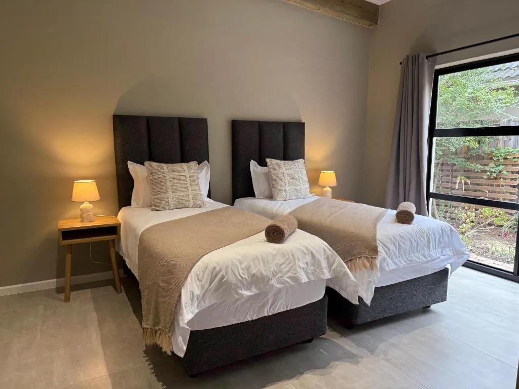 Twin bedroom with dark headboards, warm lighting, and garden view