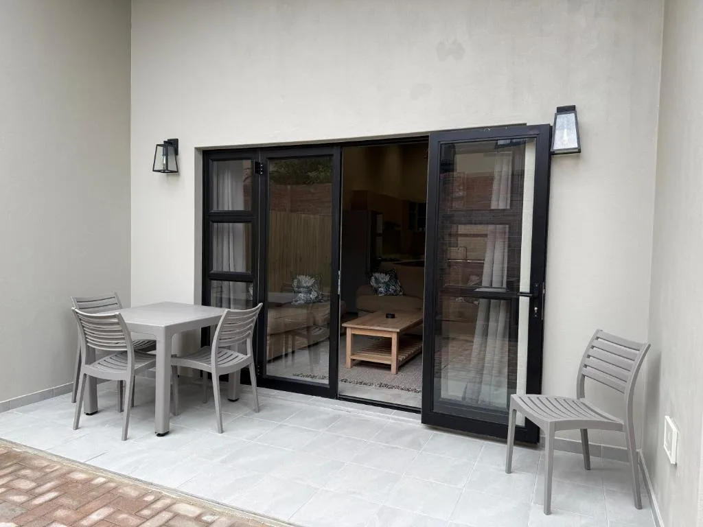 Patio area with dining table, chairs, and glass doors to lounge