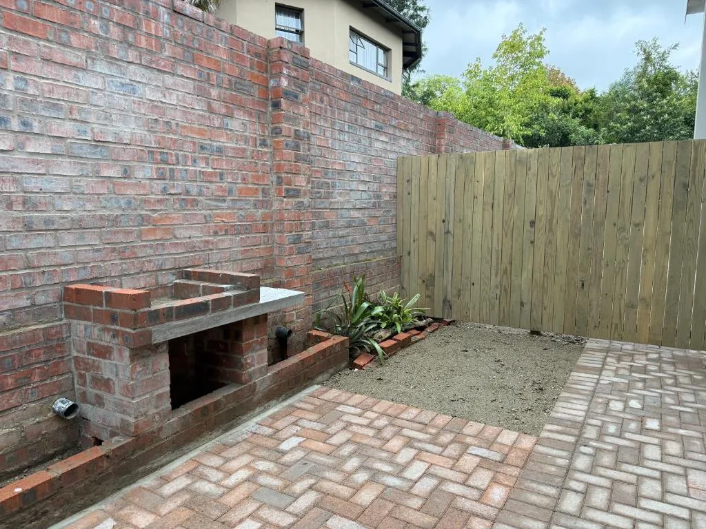 Outdoor patio with built-in brick braai and wooden fence surround
