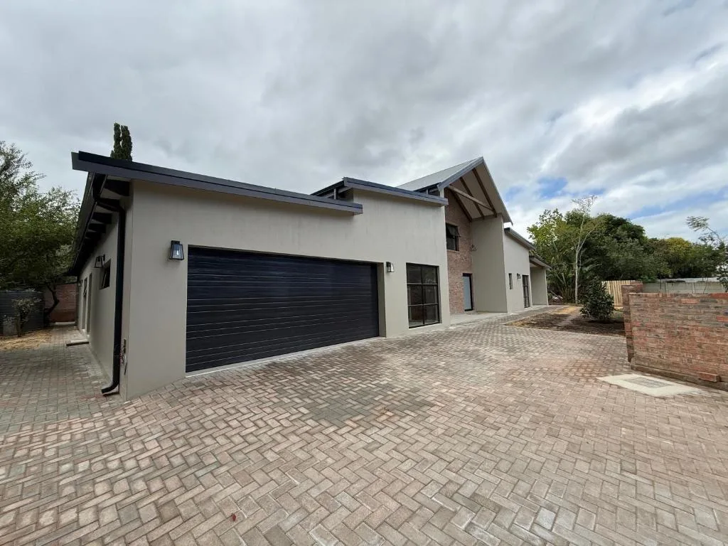 Modern white and brick home with black garage door and paved driveway