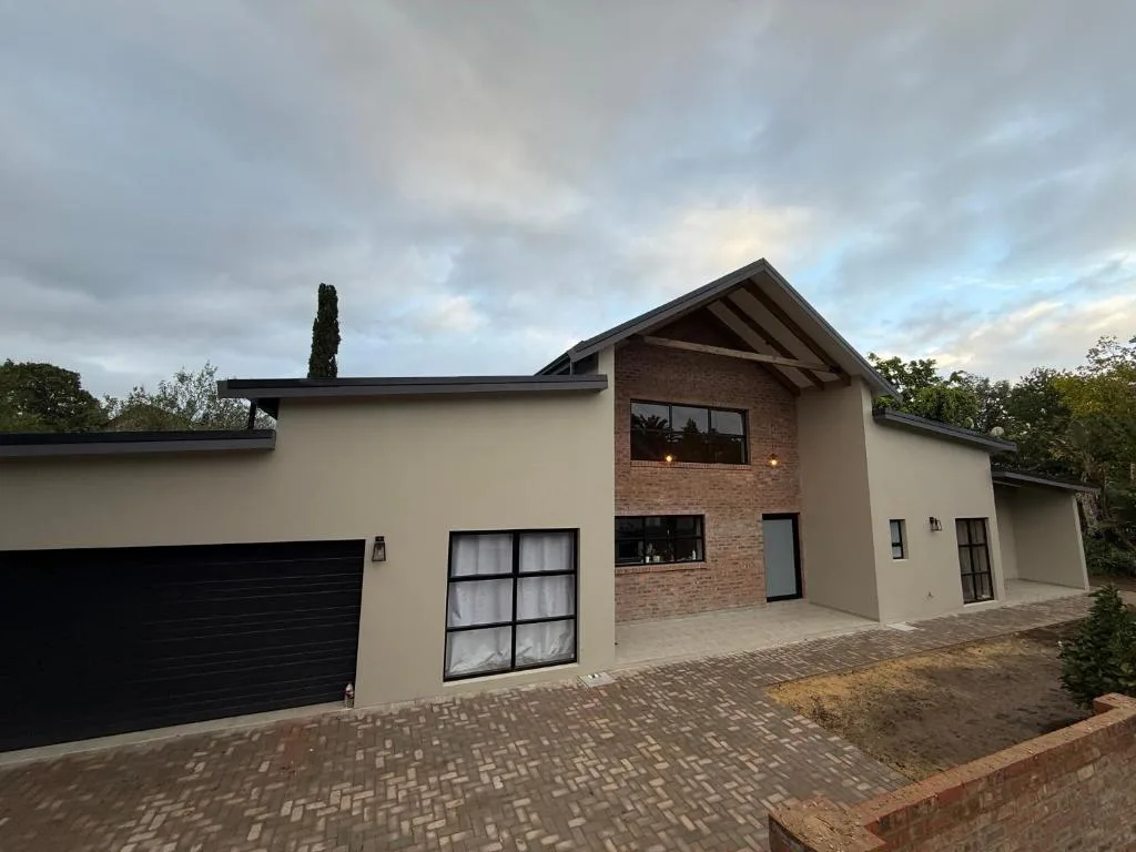 Modern cream and brick house with black garage and paved driveway